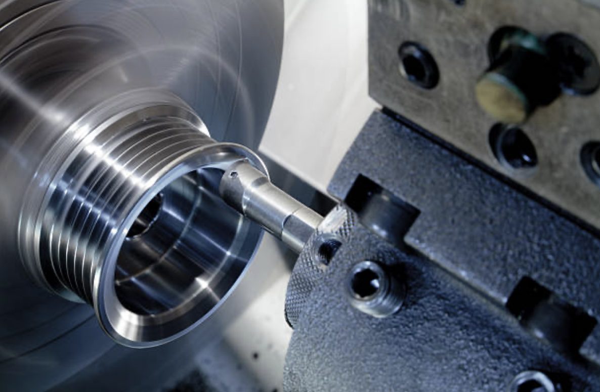Close-up of a precision lathe machining a metal component, showcasing the spinning process and intricate details of the part being shaped.